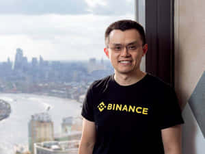穿Binance T恤的男人在窗邊微笑，城市景觀