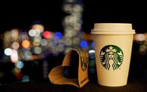 Starbucks咖啡杯和杯套在窗台上，背後有模糊的城市燈光。