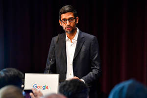 穿西裝的男子在Google活動中發言，前景有觀眾。