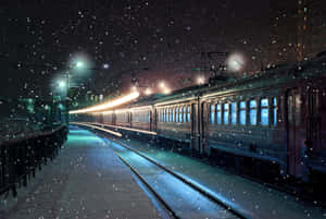 大雪覆蓋夜晚的火車站，燈光閃爍，火車在軌道上。
