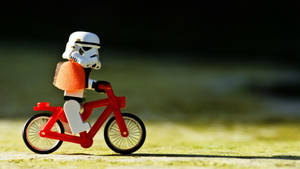LEGO風暴兵在陽光下在草地上騎著一輛紅色單車。