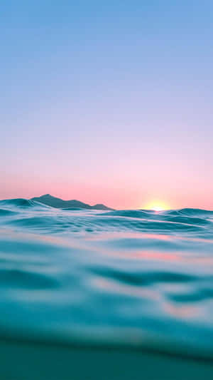 夕陽下的海浪，遠山，粉紅色和藍色的天空