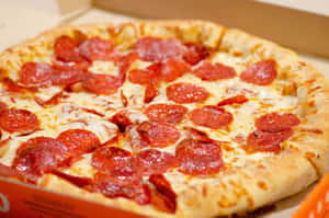 一個紙箱中的意大利辣香腸薄餅，帶有融化的芝士和金黃色的餅皮。