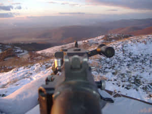 步槍從白雪覆蓋的山丘瞄準山谷，夕陽