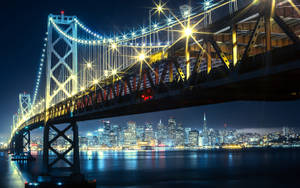 夜間照亮的海灣大橋，三藩市天際線與水面倒影。