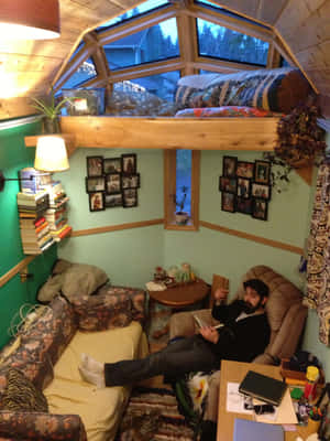 男子在舒適的木屋中閱讀，有木樑和書架。