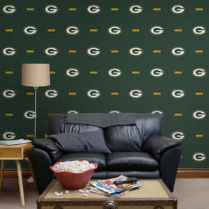 黑色皮革沙發前有 Green Bay Packers 牆紙，咖啡桌上有爆米花和雜誌。 — 綠灣包裝工 GIF 壁紙