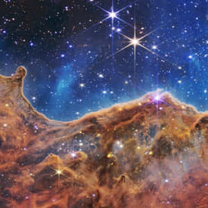 深藍色太空中帶有明亮星星的鮮豔橙色星雲雲團。 — 銀河 壁紙