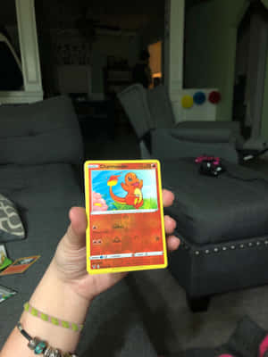 一隻手喺客廳入面揸住一張Charmander Pokémon卡。