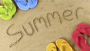 色彩繽紛的拖鞋框住了沙灘上寫著的「Summer」字樣。 — 夏天 壁紙