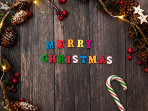 Merry Christmas 以彩色字母拼寫在木質背景上，帶有節日裝飾。