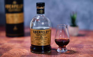 一瓶Aberfeldy威士忌和品酒杯放在木桌上。