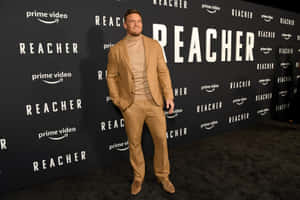 身穿米色西裝的男子在Reacher首映活動的黑色地毯上。