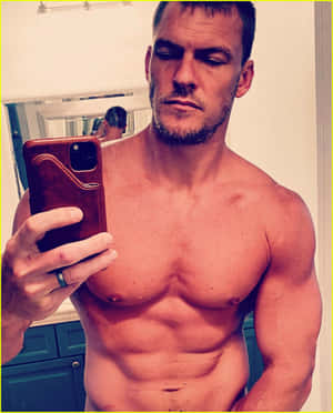 一個有鬍鬚的肌肉男在浴室對著鏡子自拍。