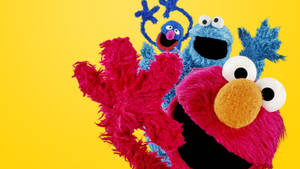 Elmo 和 Cookie Monster 公仔在黃色背景前微笑舉起手臂。