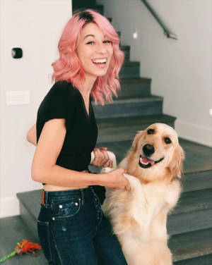粉紅色頭髮女性和金毛尋回犬在樓梯上微笑