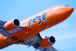 橙色Mango Airlines飛機在清澈藍天中飛行
