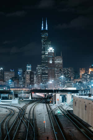 夜晚的城市場景，有發光的摩天大樓和交錯的火車軌道。
