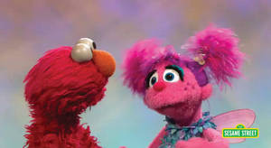 Elmo 和 Abby Cadabby 在芝麻街上互相微笑。