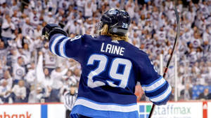 冰球運動員Laine（29號）在場館內高舉手套，面對歡呼的人群慶祝。 — 運動 壁紙