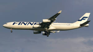 芬蘭航空飛機放下起落架，在多雲的天空背景下下降。