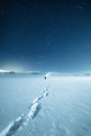 一個人在星空下的雪地中獨自行走。