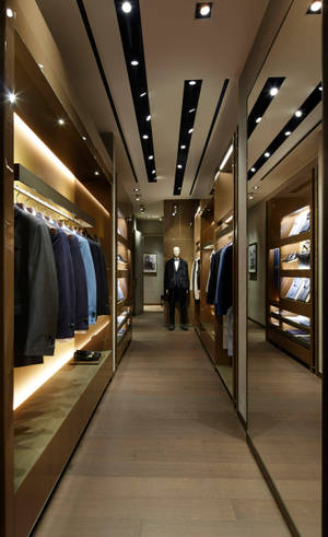 一間高級男士服裝店，配有木質貨架和穿著西裝的人體模型。 — Moto Pad 70 Pro 壁紙
