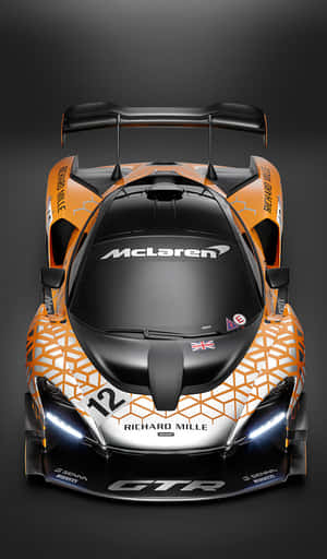 橙色和黑色麥拿倫 Senna GTR 賽車從上方觀看，帶有發光車頭燈。 — Galaxy Tab A 壁紙