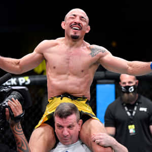 MMA拳手在八角籠內被教練扛在肩上慶祝勝利。