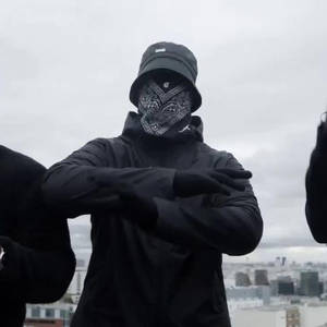 身穿黑色街頭服飾和頭巾的人，在灰色天空下的城市天台