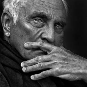 黑白畫面中，長者用手遮住嘴巴的臉部特寫。
