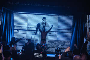 摔角手在藍色燈光下與歡呼的粉絲一起在舞台上慶祝勝利。 — 摔角 GIF 壁紙
