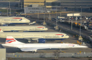 英國航空飛機停泊在機場停機坪，背景有客運大樓和地面車輛。