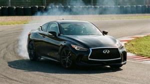 黑色 Infiniti 跑車在賽道飄移，伴有輪胎煙霧