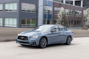 銀色 Infiniti 房車在城市街道上行駛，經過現代建築和樹木。