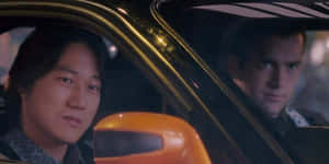 兩個男人夜晚在車裡，一個向前看，另一個斜視側面 — 狂野時速 壁紙