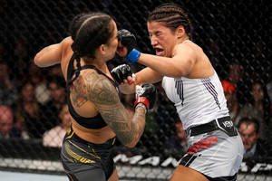 兩名女性MMA拳手在鐵籠內進行高能量比賽。 — 運動 壁紙