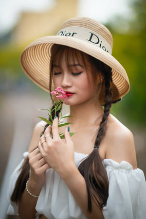 戴草帽的女性在戶外聞粉紅色的花