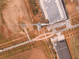 從上方俯瞰乾旱土地上的風力渦輪機和太陽能農場，有道路和建築物。