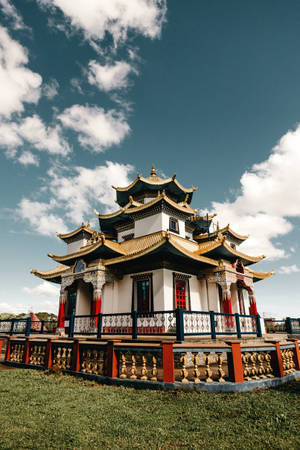 一座傳統亞洲寺廟，擁有金色屋頂和紅色柱子，在藍天白雲下。 — 唐人街 GIF 壁紙