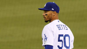 身穿道奇隊球衣的棒球選手 Mookie Betts 在夜晚的球場上。