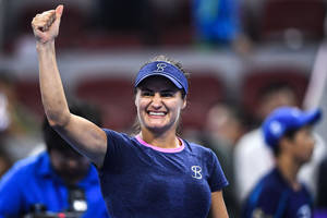 女網球運動員在燈光球場上微笑並高舉拳頭慶祝勝利。 — 網球 壁紙