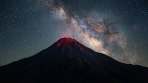 火山在夜間噴發，星空下可見銀河系