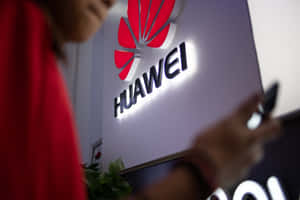 在Huawei標誌牌附近手持電話的人士（室內）