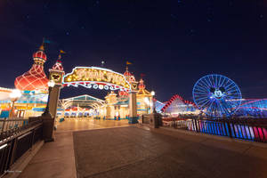 夜晚 Pixar Pier 主題公園入口，發光的遊樂設施和星空。