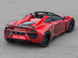 紅色McLaren敞篷跑車，黑色輪胎，停在瀝青上。