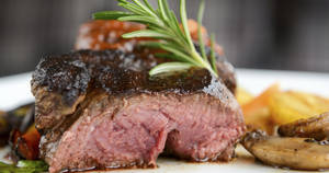 切片 medium-rare 牛扒，配上迷迭香同烤蔬菜，放喺白色碟上。