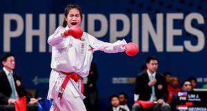 身穿白色制服和紅色手套的女性跆拳道選手在比賽中出拳。
