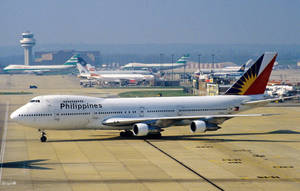 菲律賓航空波音747喺機場停機坪上，有其他飛機同控制塔。