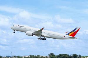菲律賓航空飛機放下起落架，在藍天白雲中降落。